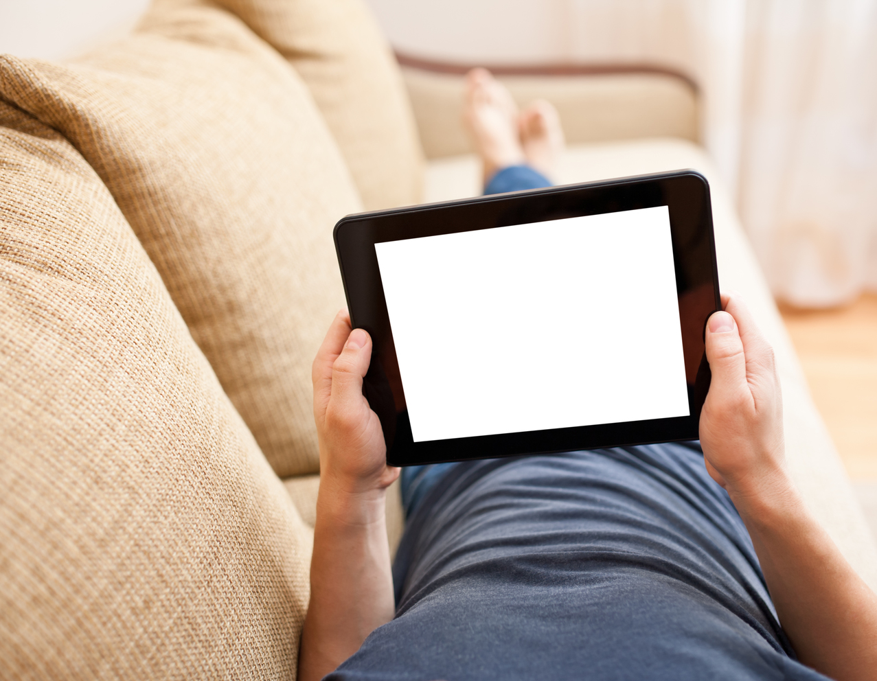 Man relaxing with tablet pc, laying on sofa